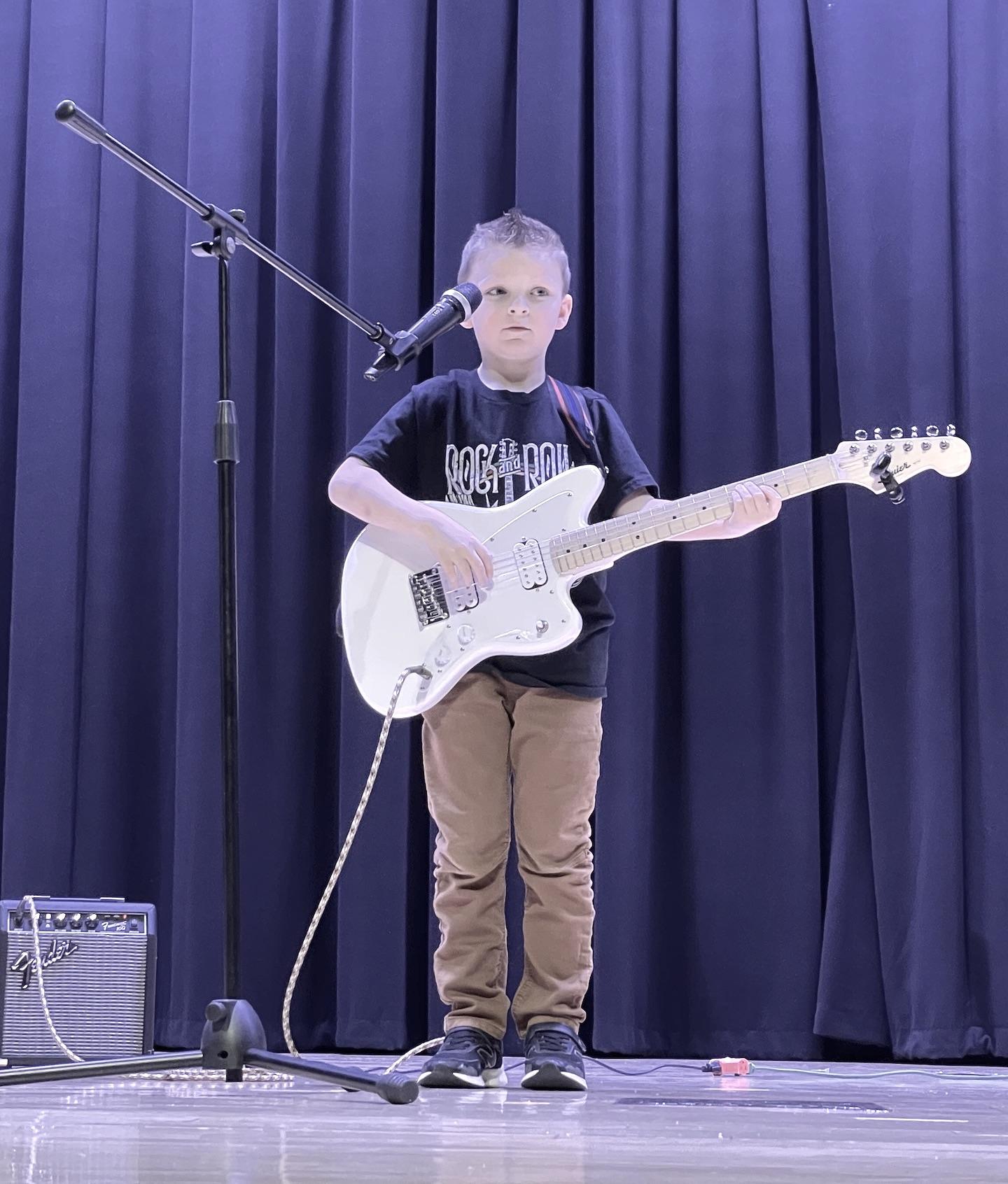 First-grader Waylon Fawcett playing the electric guitar