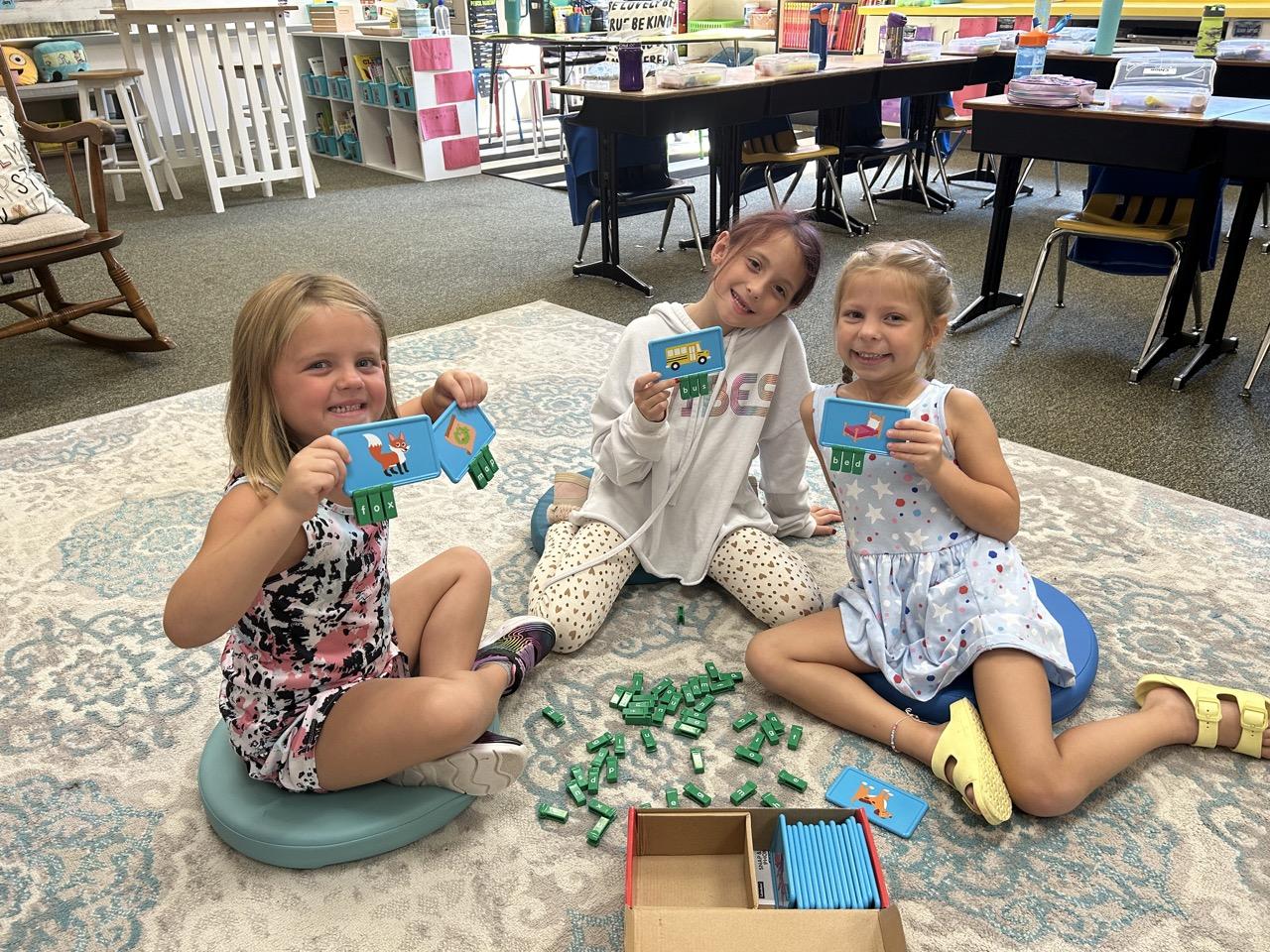 Chloe Zeminski, Gemma Armbrust and Clara Briscoe work together on their phonics skills to build new words with an interactive snap and build center