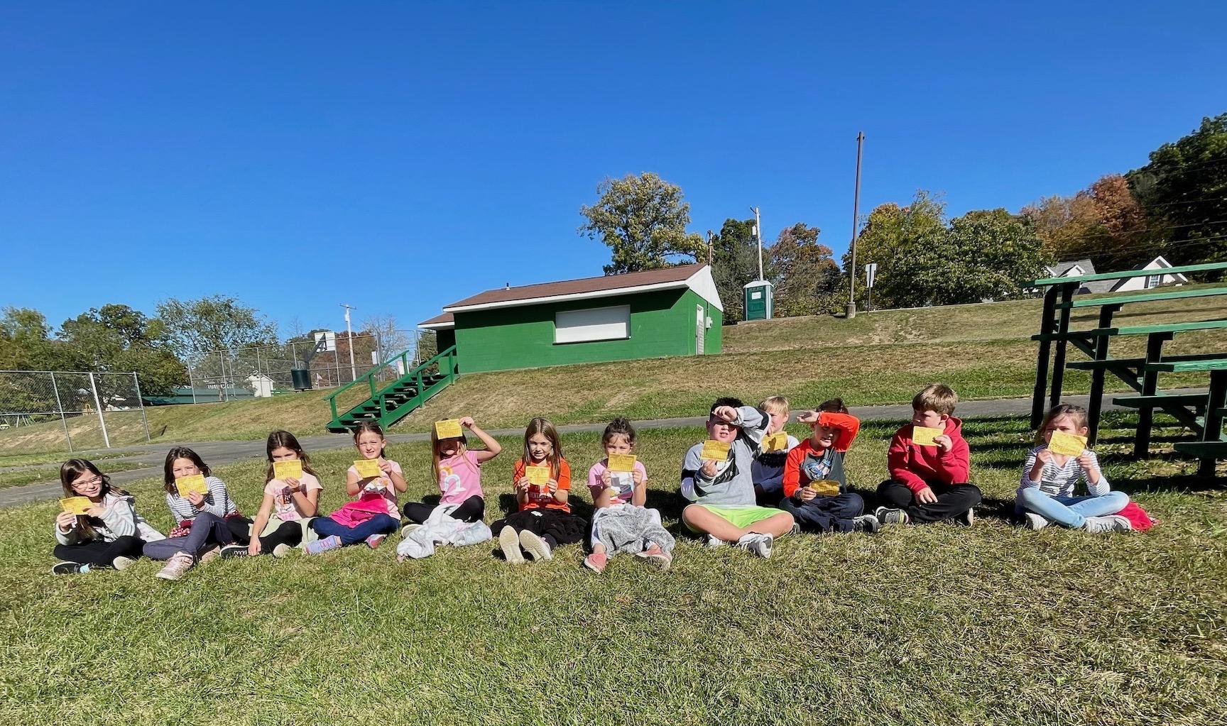 Mrs. Giovannitti’s 1st-grade class rests after walking laps on the track