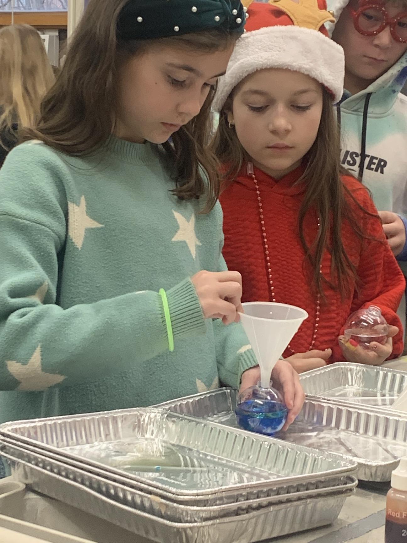5th-graders Sophia Braun and Evelyn Borst watch the bubbling reaction